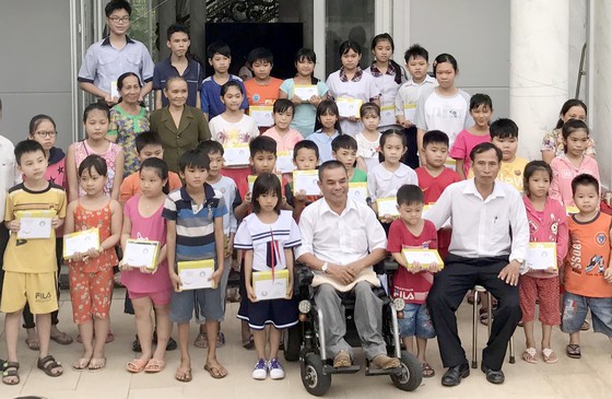 Ông Trần Văn Triệu (ngồi xe lăn) trao học bổng cho học sinh nghèo